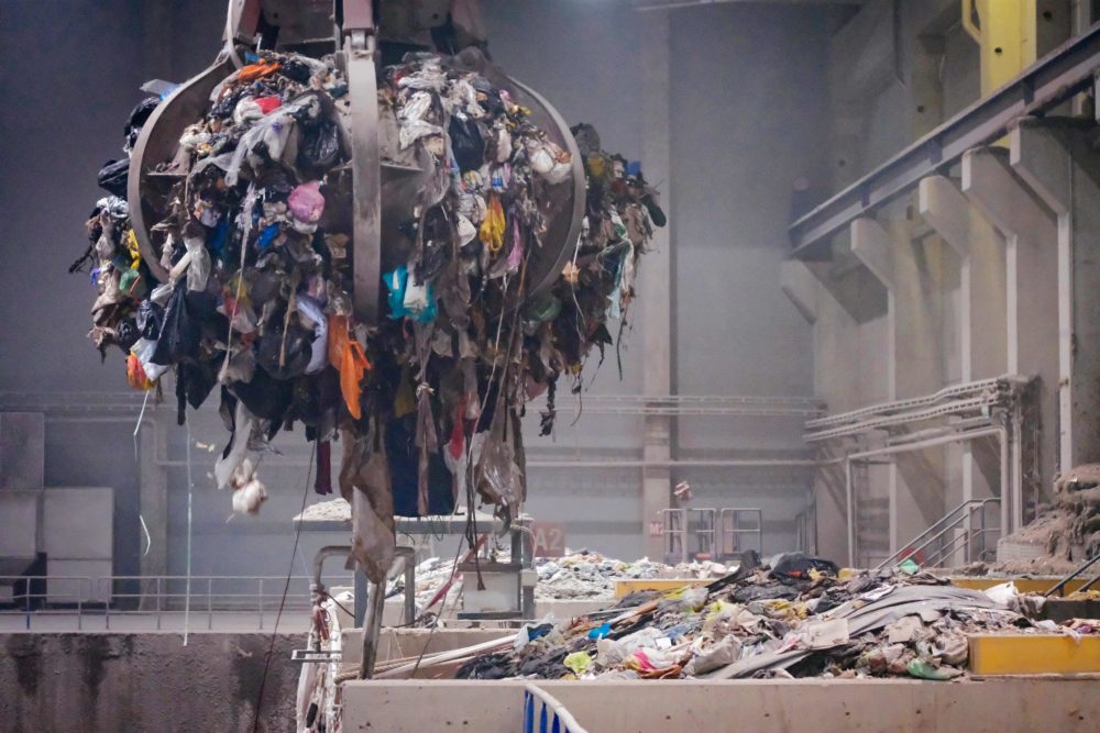 An overhead crane sorts garbage destined for an incinerator's furnace in a Waste-To-Energy facility in Finland.