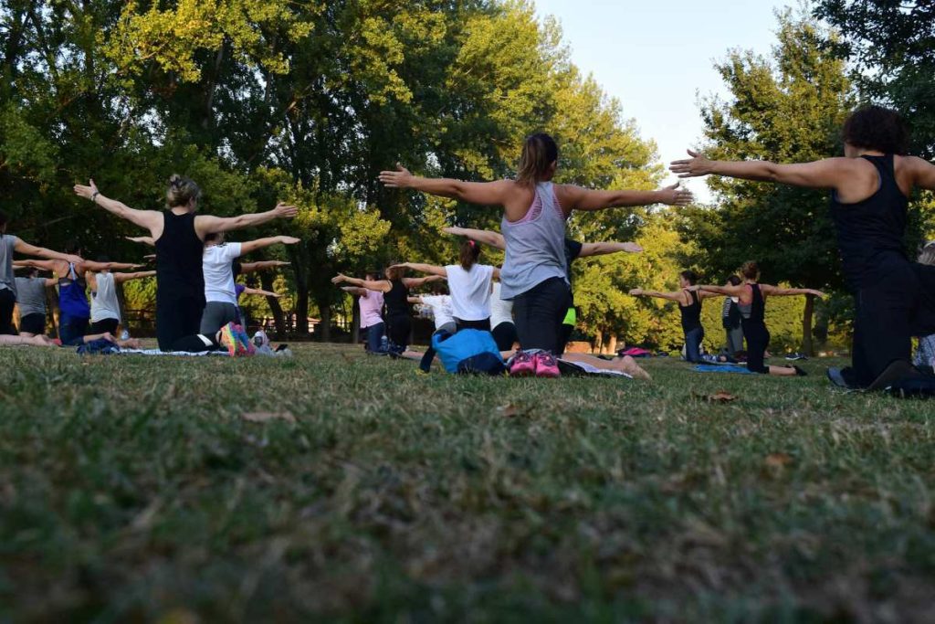 Residents participating in a yoga class on a grassy field showcasing holistic wellness programs ideal for seaside communities.