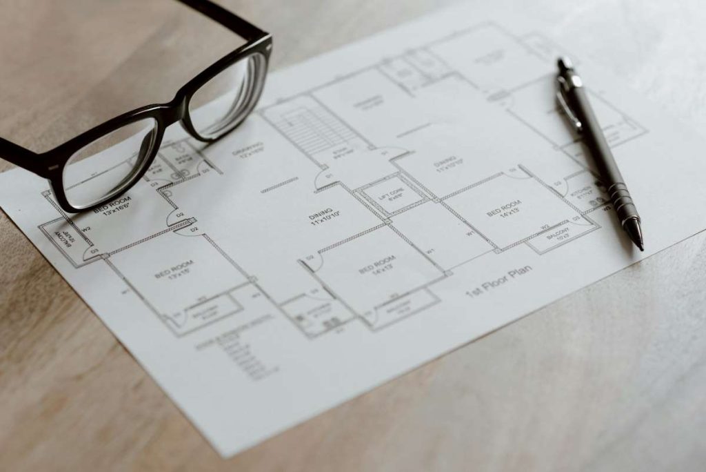 Architectural and engineering plans on a desk, illustrating the detailed design and planning required in house construction projects.