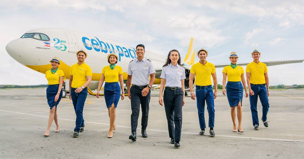 Cebu Pacific crew members, including flight attendants and pilots, walking on the tarmac in front of a Cebu Pacific Airbus A330 aircraft.